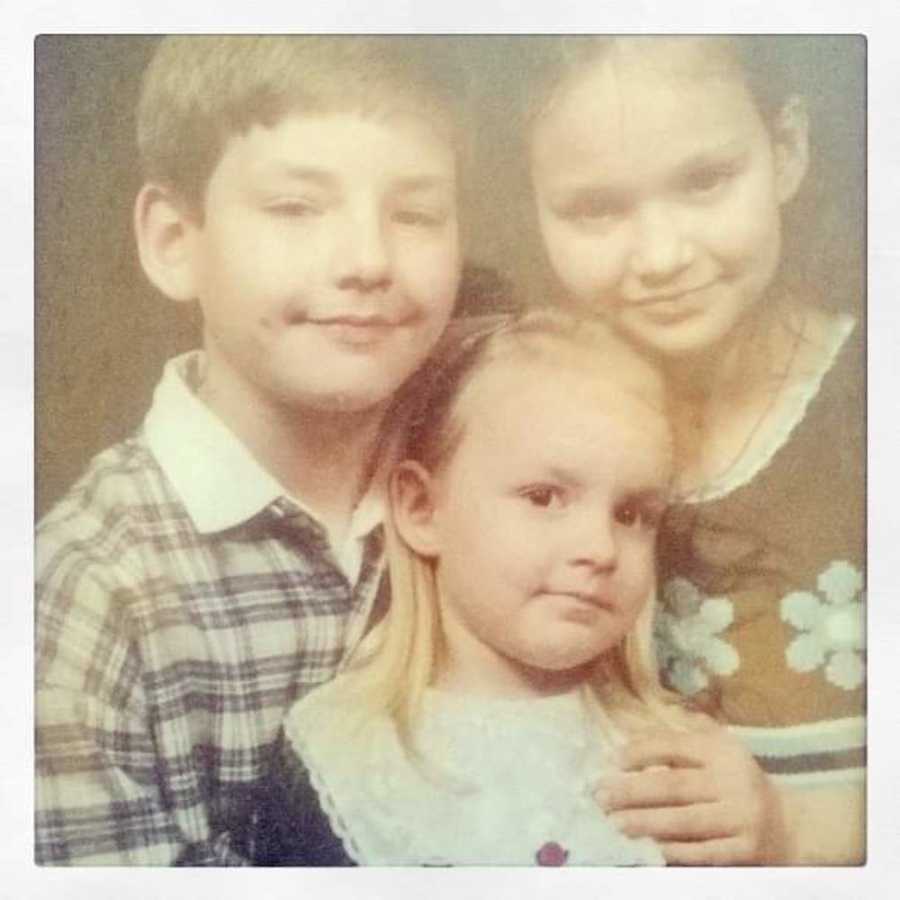 Little girl with diabetes sits smiling with her brother and sister