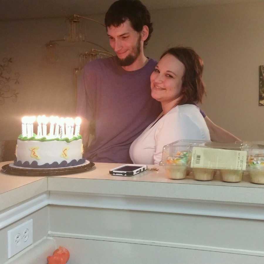 Woman with diabetes stands beside her husband as they stand at counter with birthday cake on it