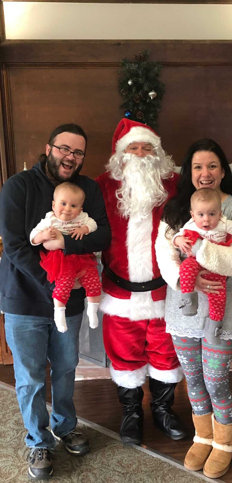 Mother and father stands on either side of mall Santa each holding a twin who has cancer