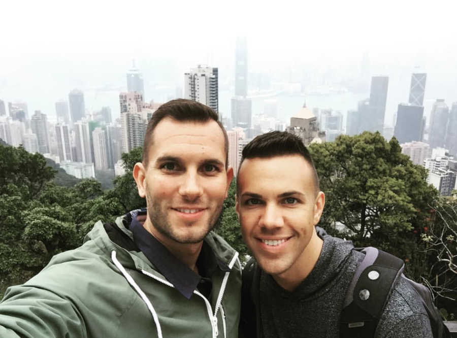 Man takes selfie with husband with city skyline in background