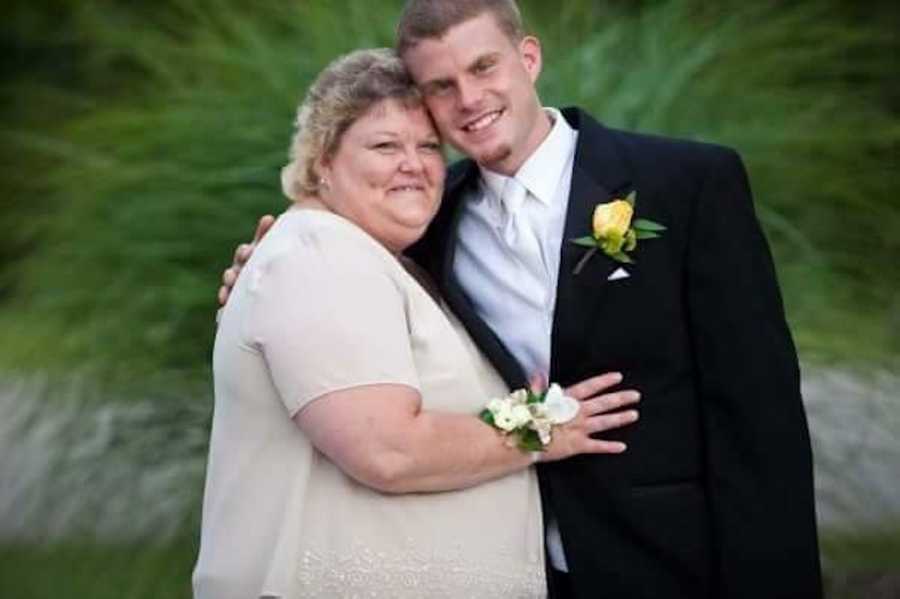 Woman with fibromyalgia and depression stands smiling with arms wrapped around her son in a suit