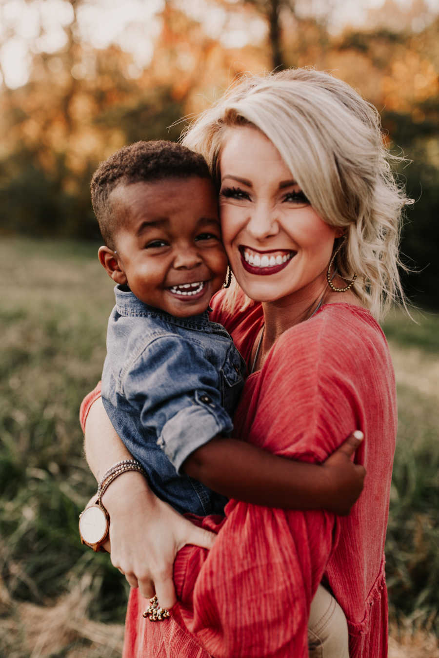 Woman smiles as she holds adopted son who is a different race than her