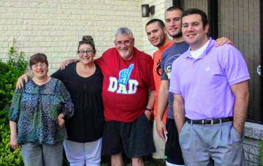 Woman stands outside of home with her parents and three brothers