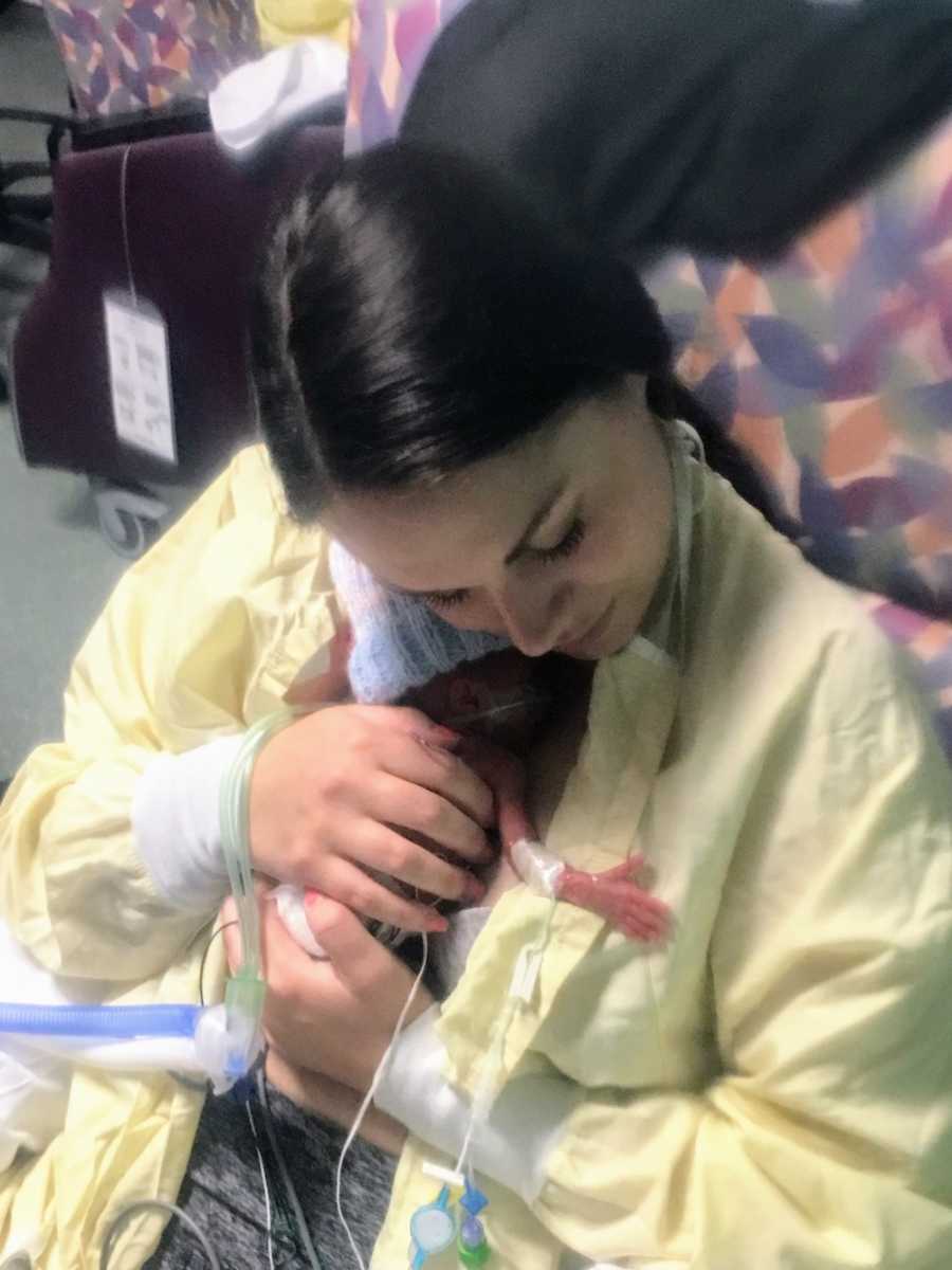 Mother sits in hospital holding her preemie baby tight to her chest