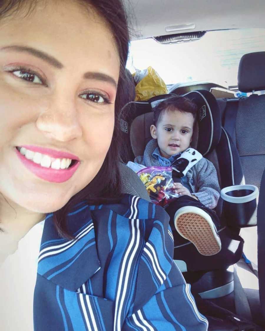 Woman who escaped abusive relationship smiles in selfie in car with son in carseat in back seat