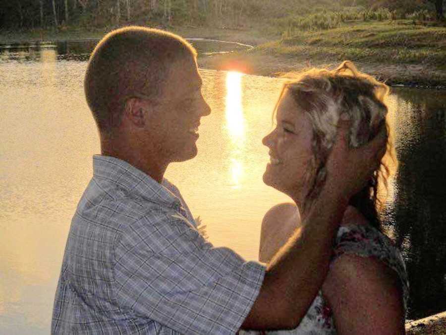 Man stands smiling at wife as he holds her head