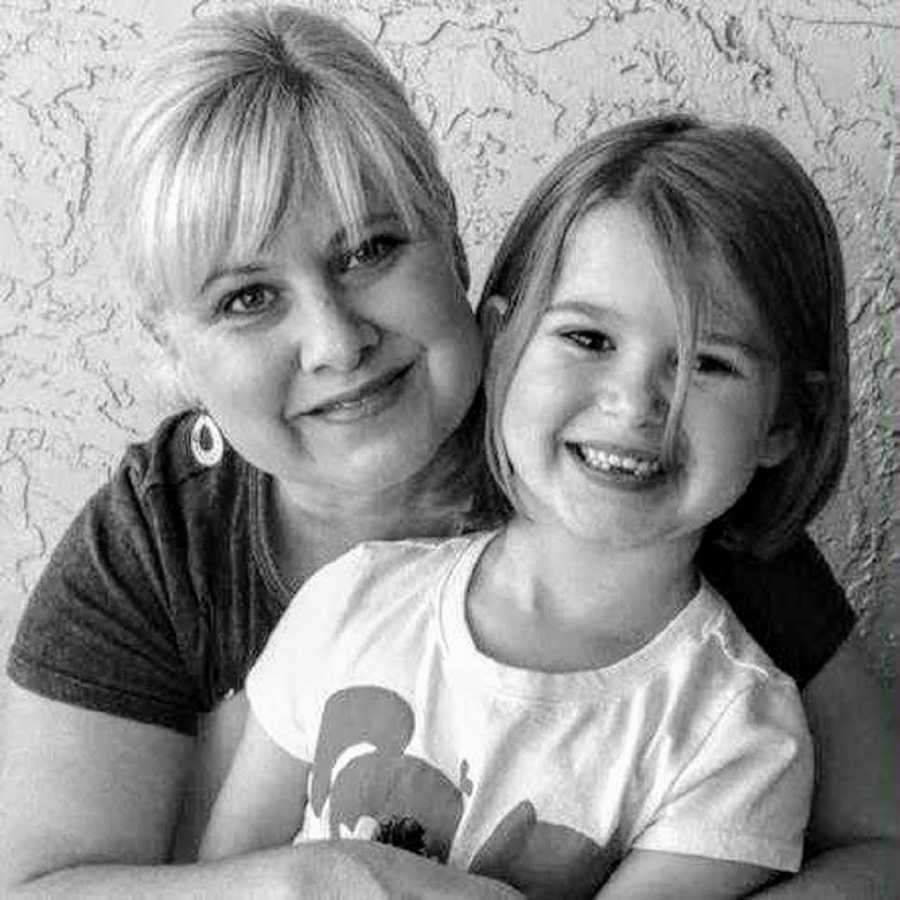 Woman smiles as she wraps her arms around her daughter