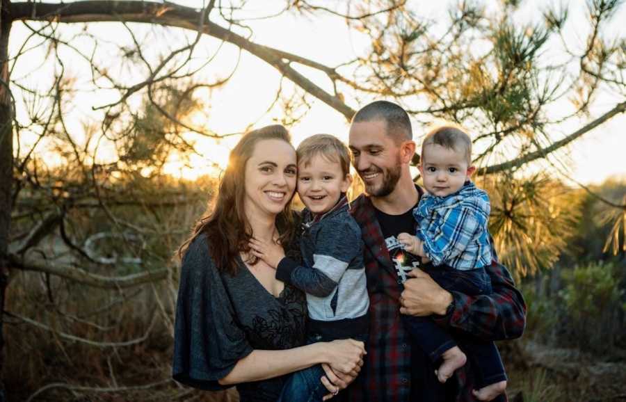 Woman with gastrointestinal problems stands outside beside husband as they hold their two sons