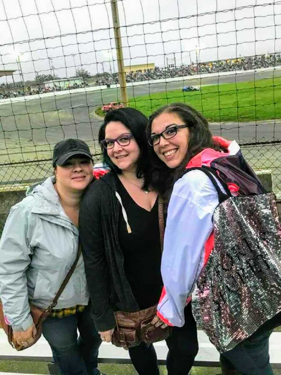 Woman who struggled with her weight stands smiling in front of race track with two friends