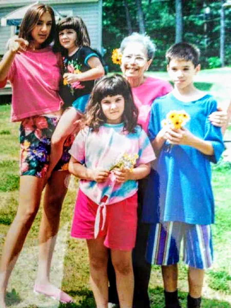 Young girl stands outside with grandmother and three siblings