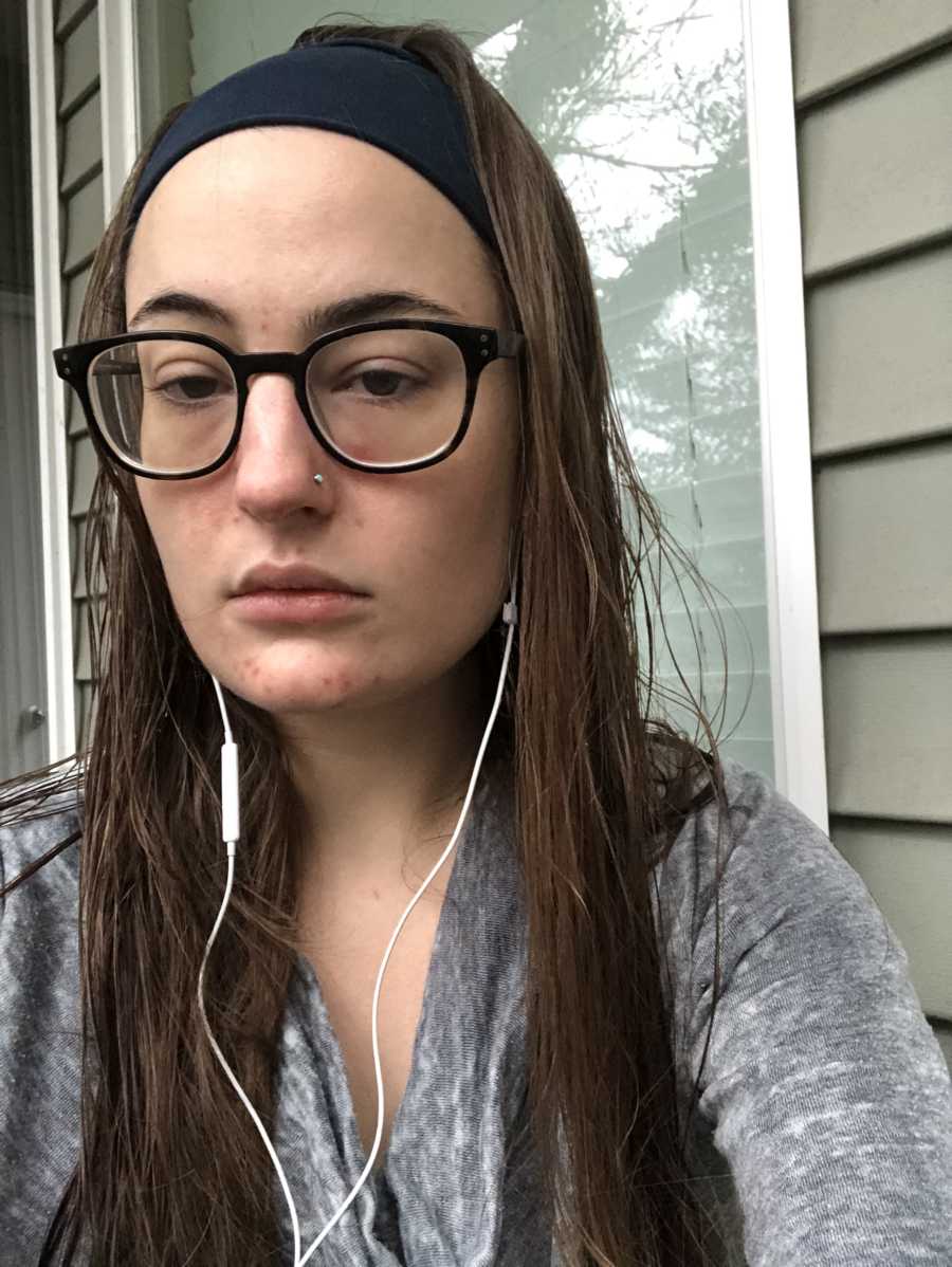 Woman with endometriosis takes selfie outside of house with head phones in 
