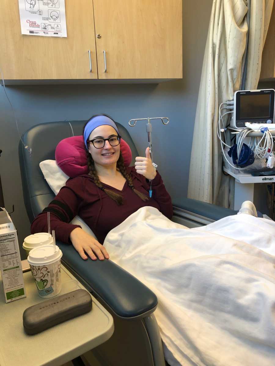 Woman who had surgery for her endometriosis sits in chair in hospital with thumb up