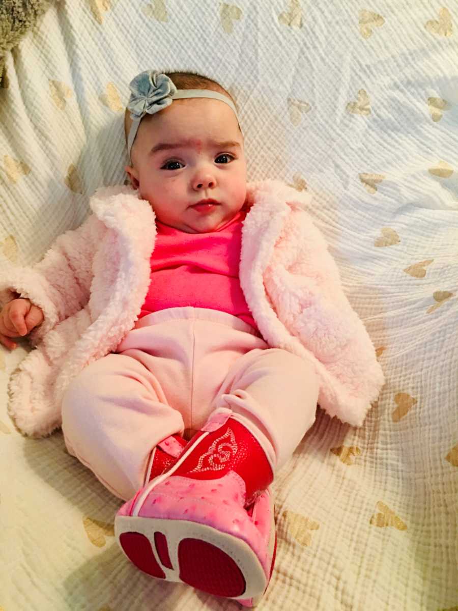 Baby girl who spent long time in NICU sits at home in all pink outfit