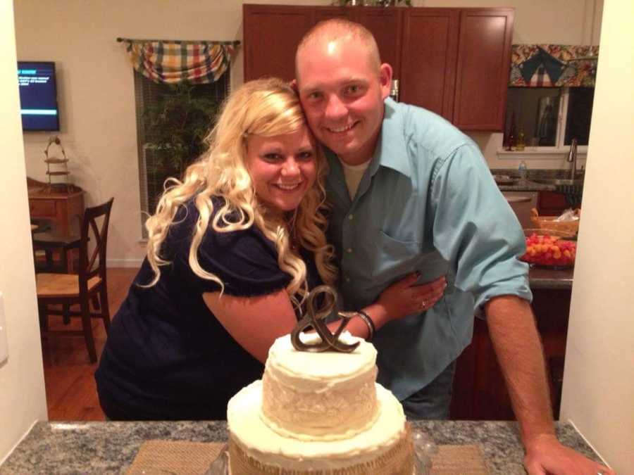 Woman stands in home hugging husband who has a vasectomy in front of cake