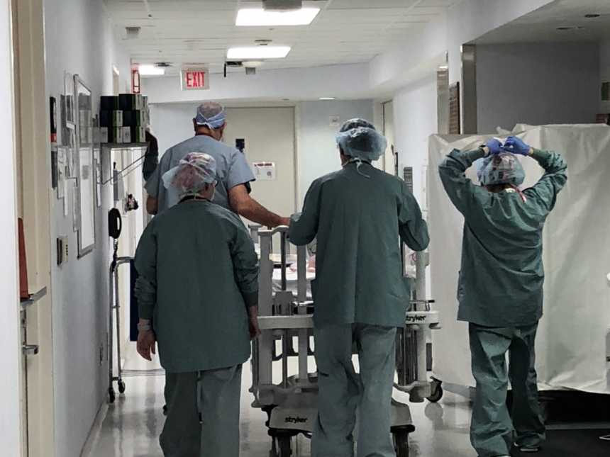 Doctors walk down hospital hallway pushing crib with baby girl with down syndrome in it