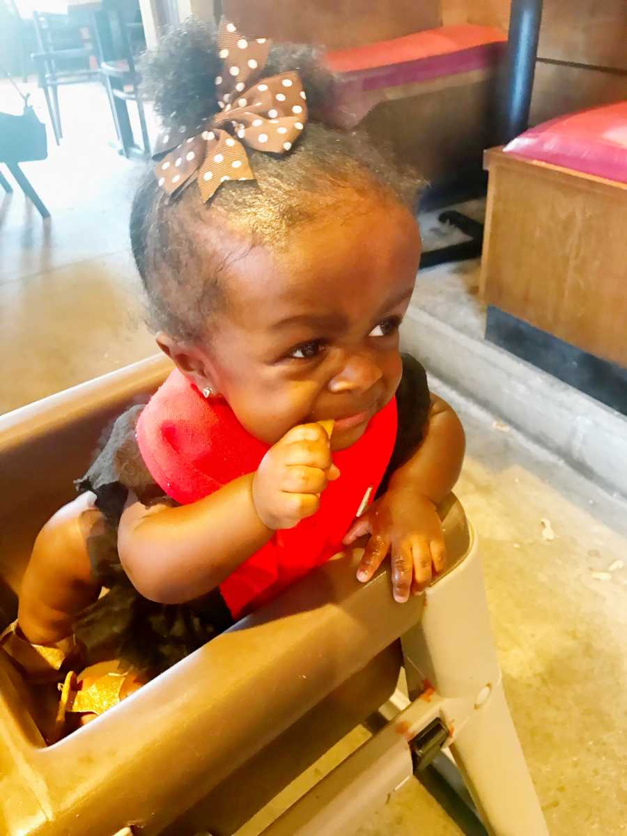 Baby girl whose mother was diagnosed with sepsis sits in high chair at restaurant eating