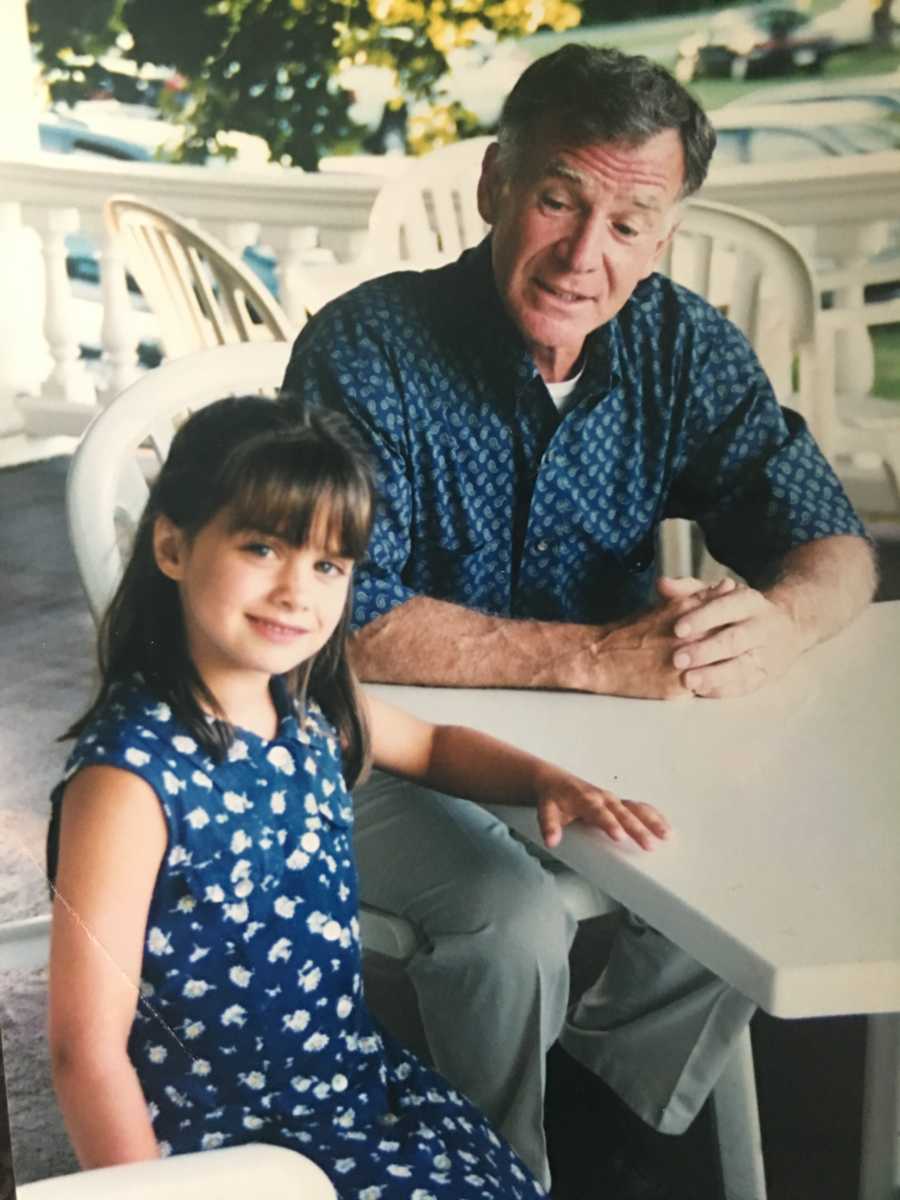 Little girl smiles as she sits at outdoor table beside her father who has since passed away