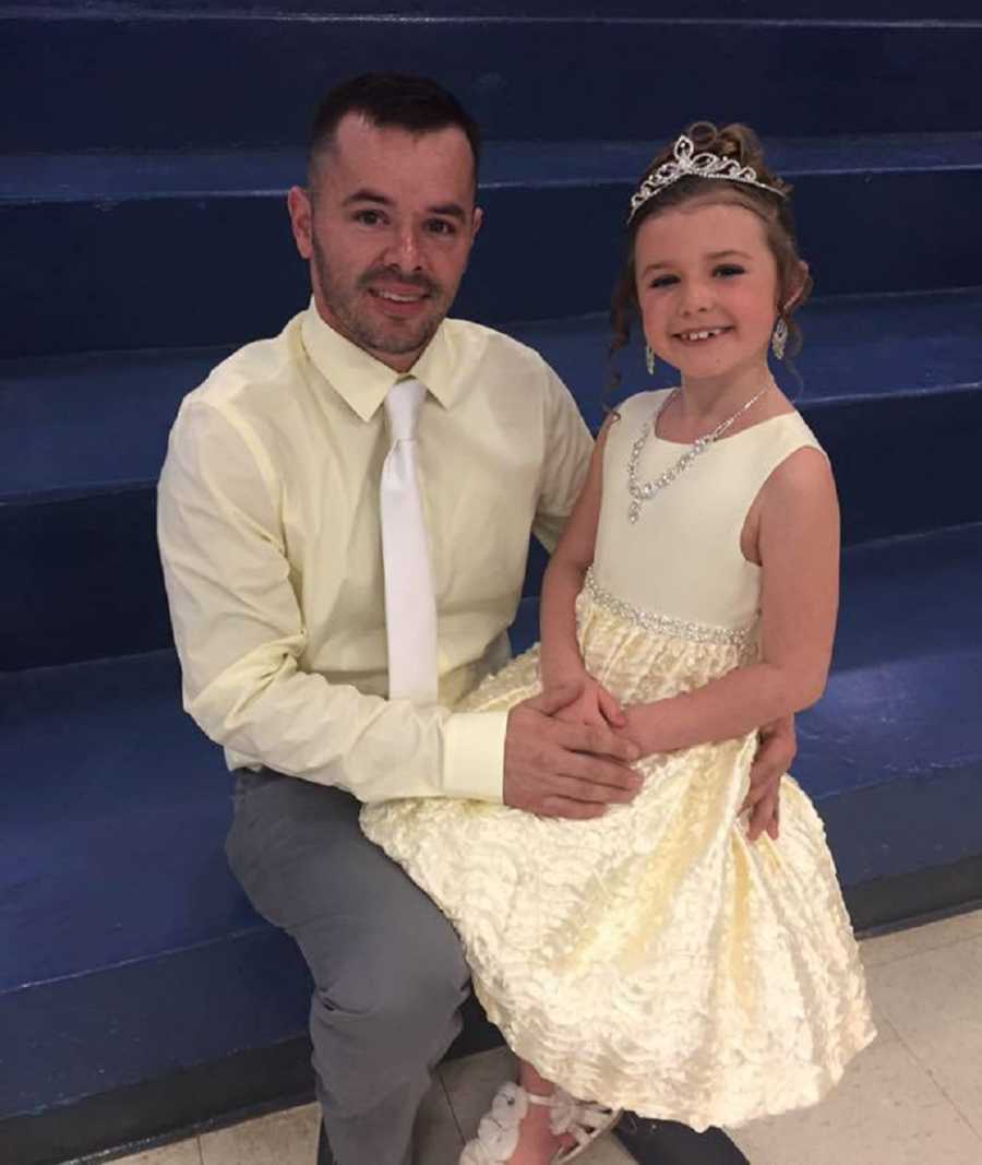 Man who has since passed away from heart attack sits on bleachers with daughter in his lap in nice dress