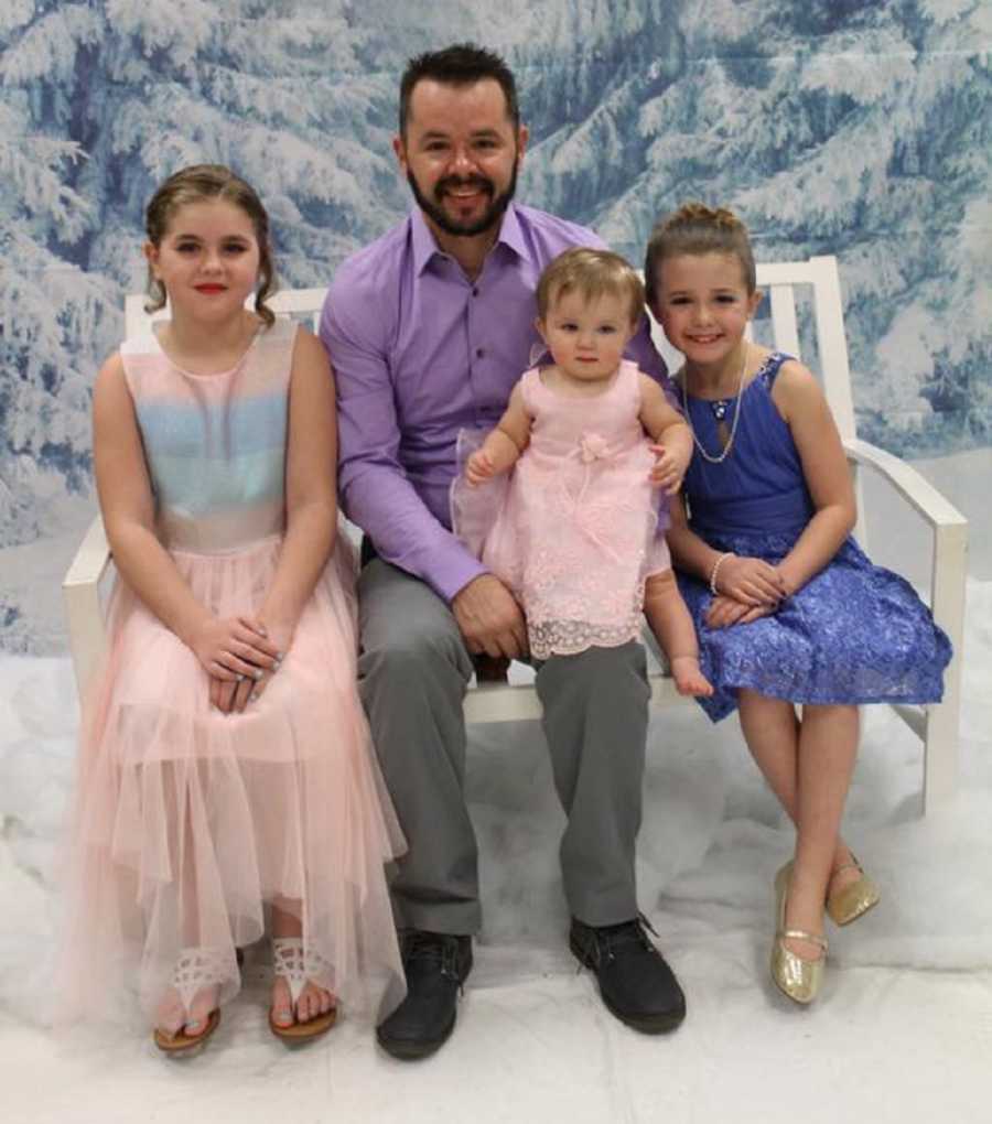 Man who had heart attack and passed away from energy drinks sits on bench with three daughters