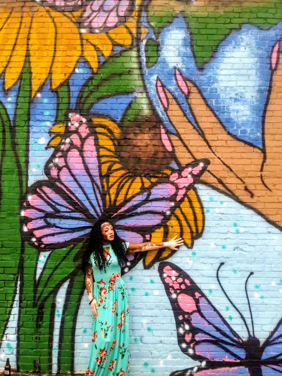 Woman with vitiligo stands in front of wall mural 