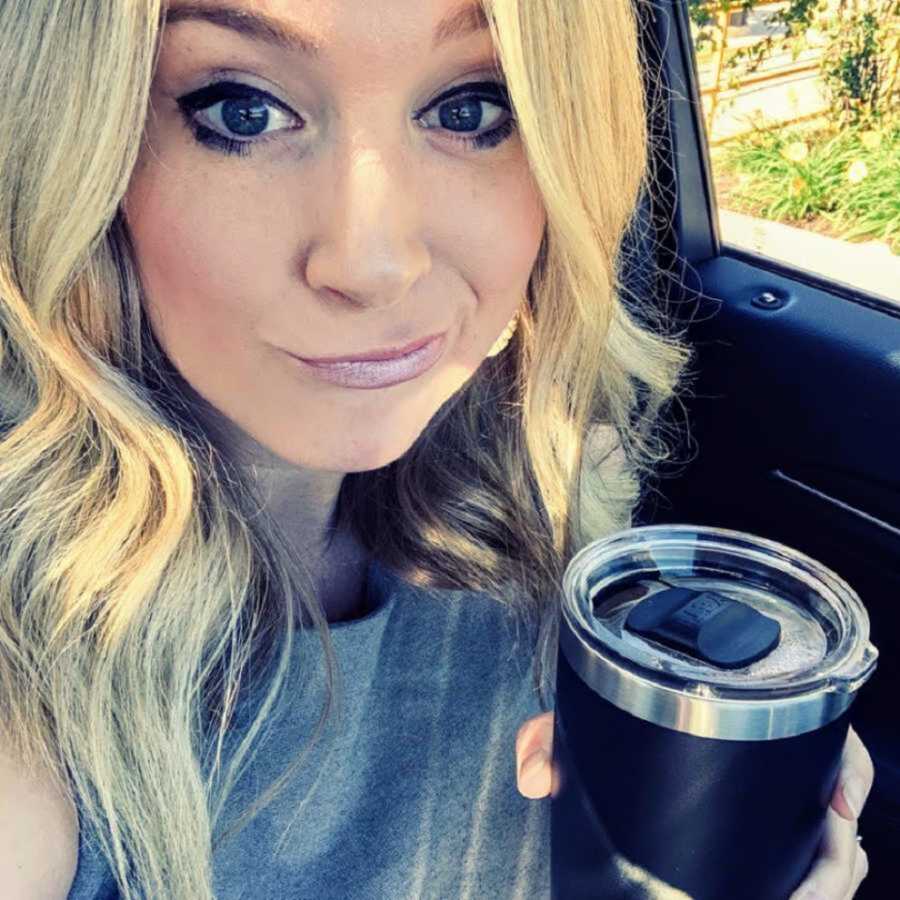 woman in car taking selfie with coffee mug