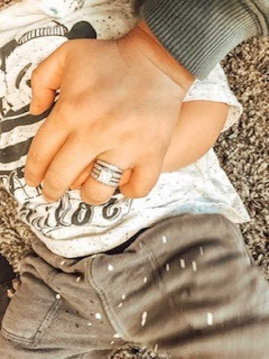 Mom with wedding ring on grasping adoptive son's hand