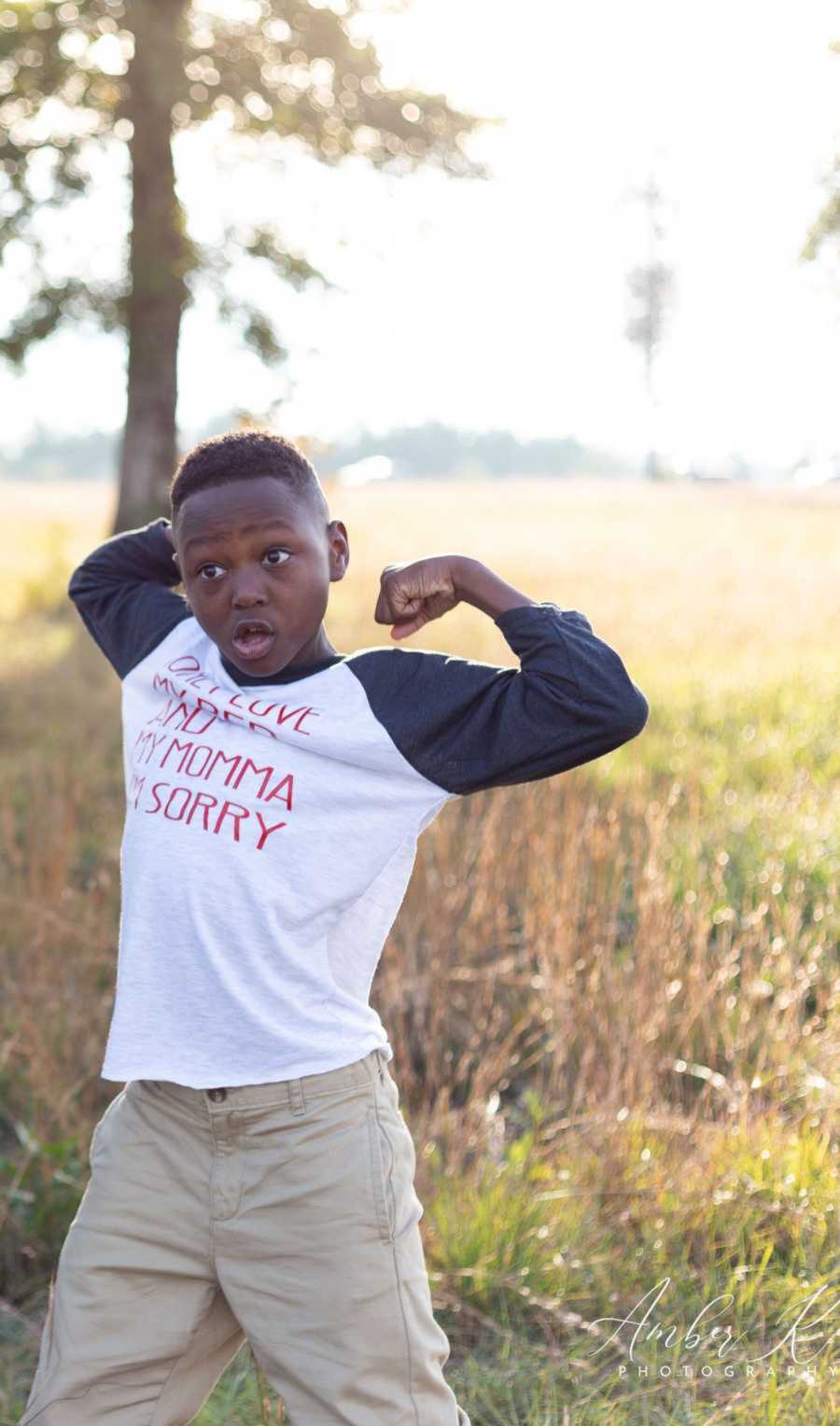 Little boy flexing arm muscles on grassy field