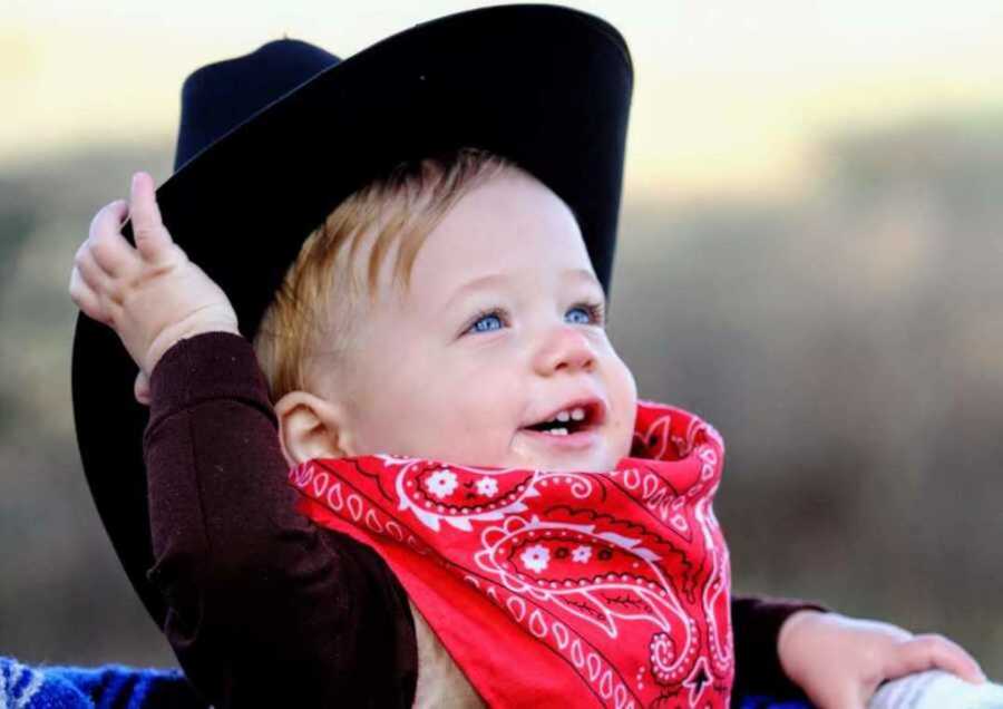 Smiling boy wearing red bandana and black cowboy hat