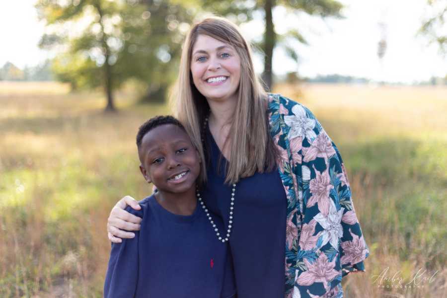 Adoptive mom embracing son at grassy field