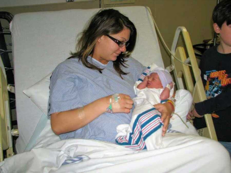 Young mom holding newborn baby in hospital bed