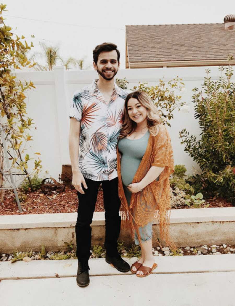 Boyfriend and pregnant girlfriend posing in backyard