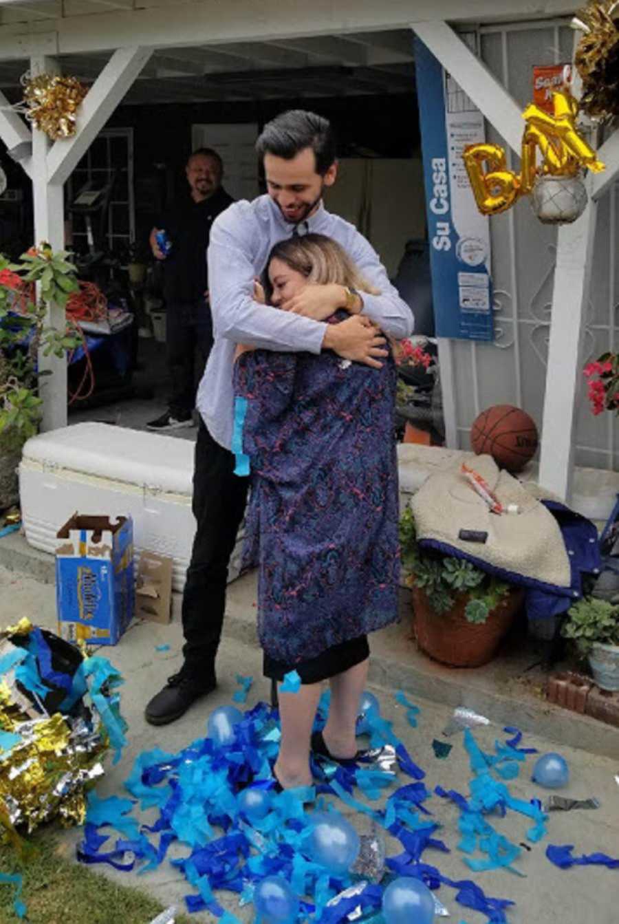 Pregnant woman embracing boyfriend at gender reveal party