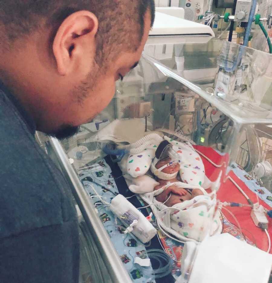 Dad gazing at premature newborn son