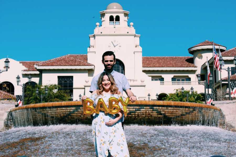 Couple holding gold balloons in gender reveal