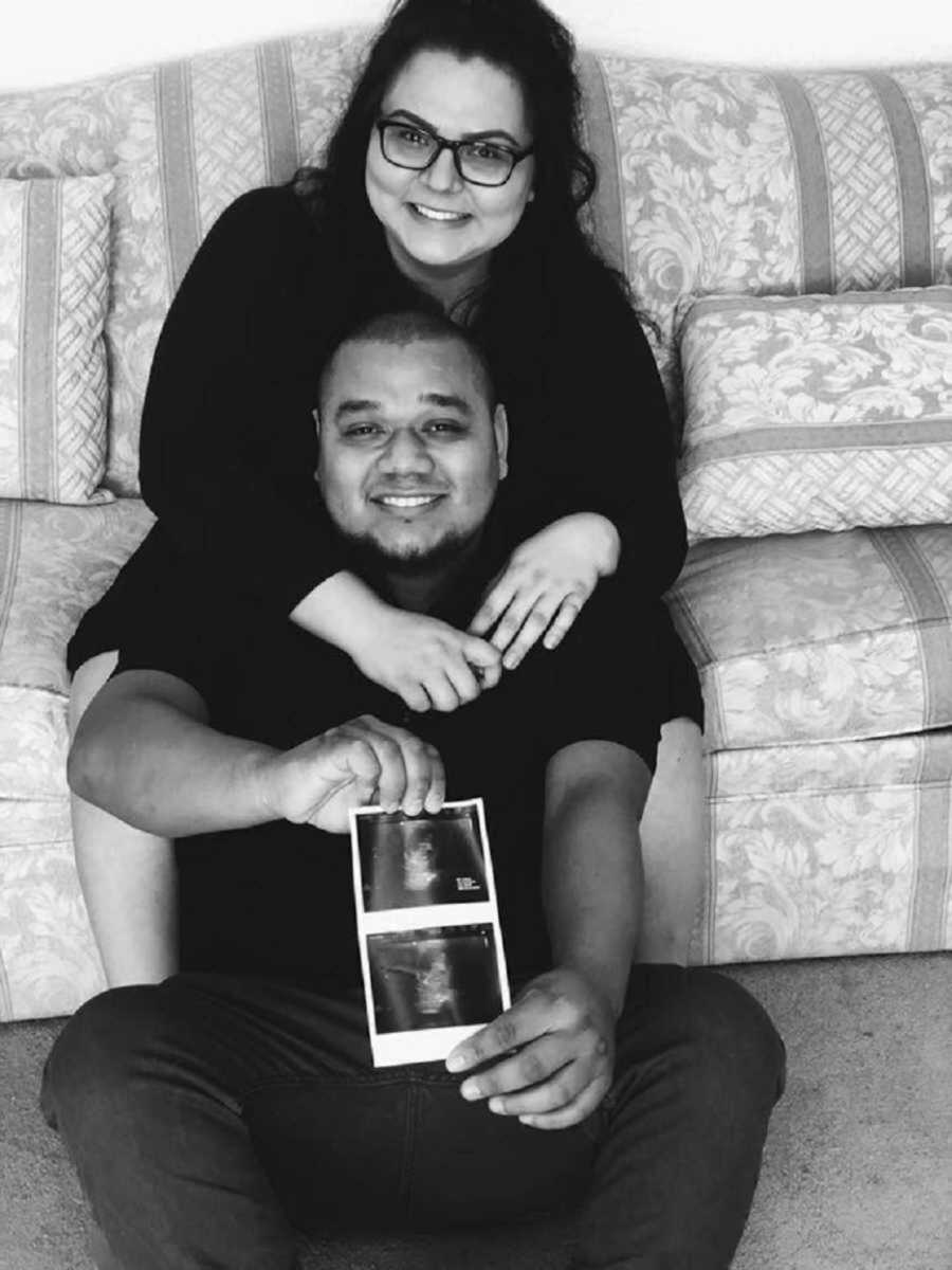 Husband and wife showing off ultrasound photos