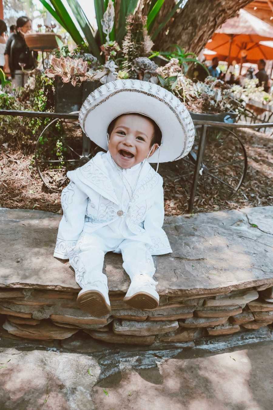 Infant wearing white sombrero and traditional Mexican suit