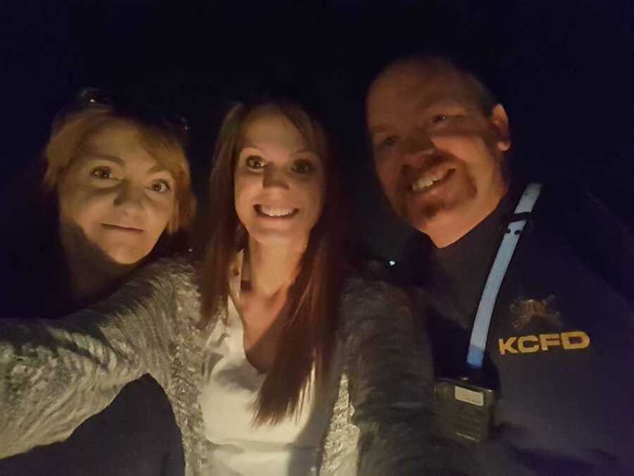 Hero firefighter smiles next to house fire survivors