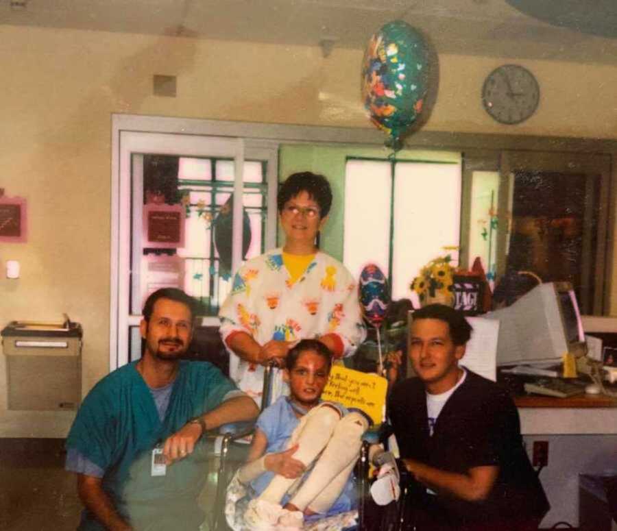 Hospital staff smile next to burn victim in wheelchair