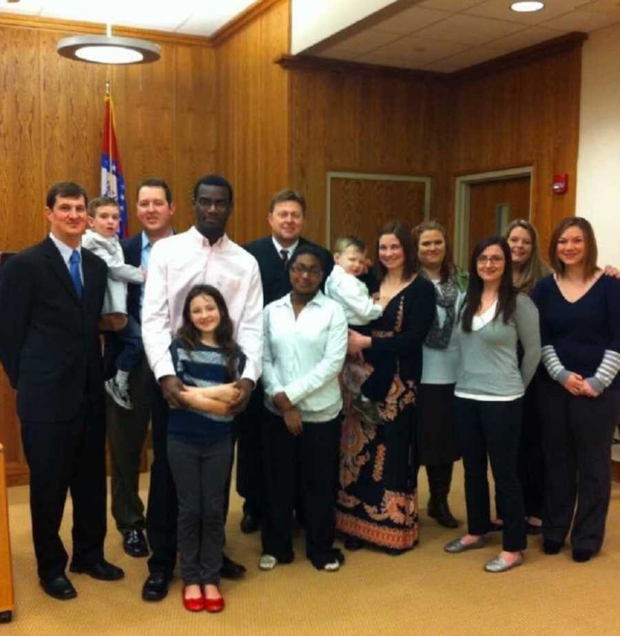 Adopted family smiling in court room alongside judge