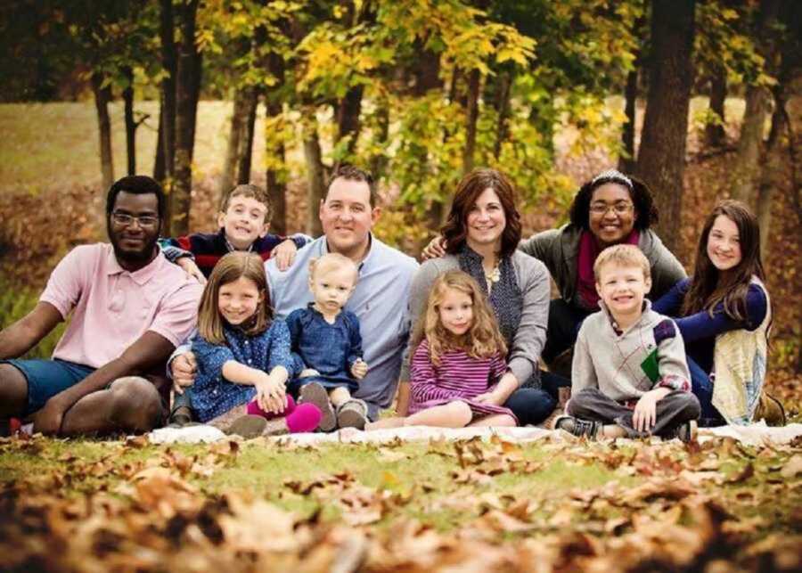 Adoptive family posing in fall foliage 