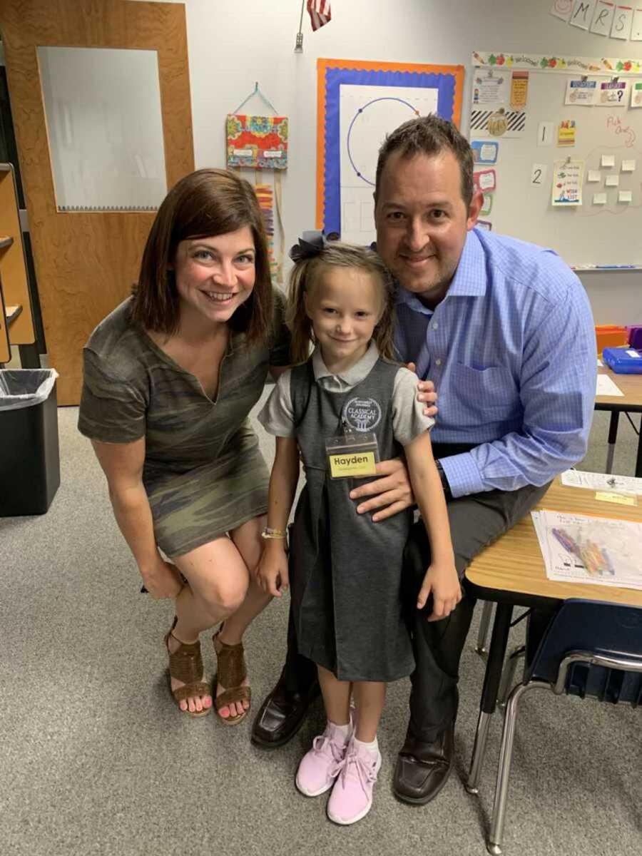 Coparents smile next to daughter in school gown