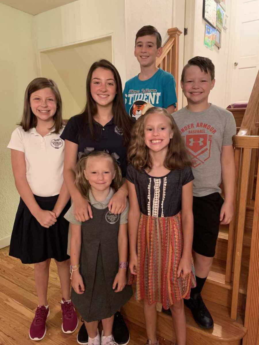 Foster family smiling together while standing in stairwell