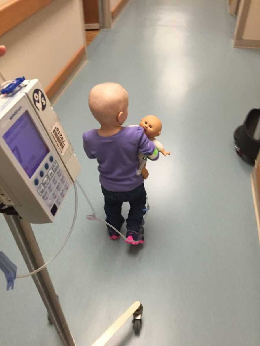 Girl with leukemia in purple shirt holding toy doll