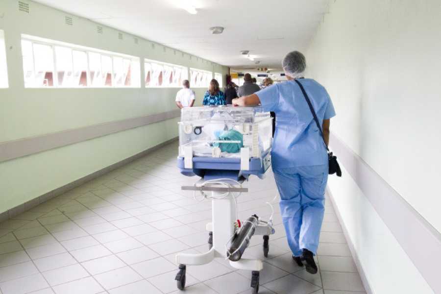 nurse pushes NICU baby in incubator through the hospital hall