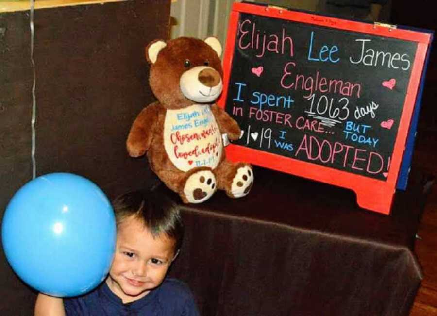 Adopted boy smiles with blue balloon