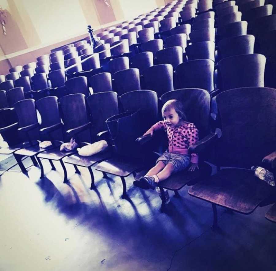 toddler sits in front row seat of theater