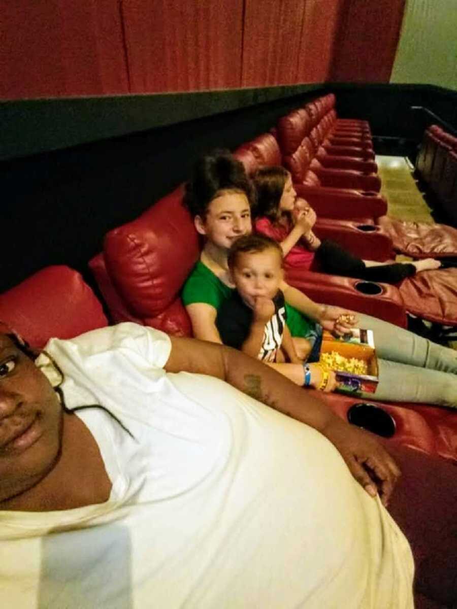 Foster family sitting in red movie theater chairs