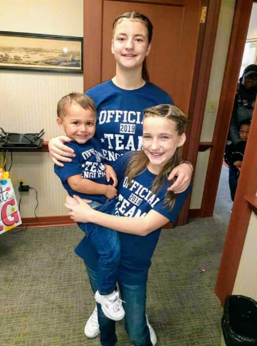 Three adopted children pose in matching blue shirts