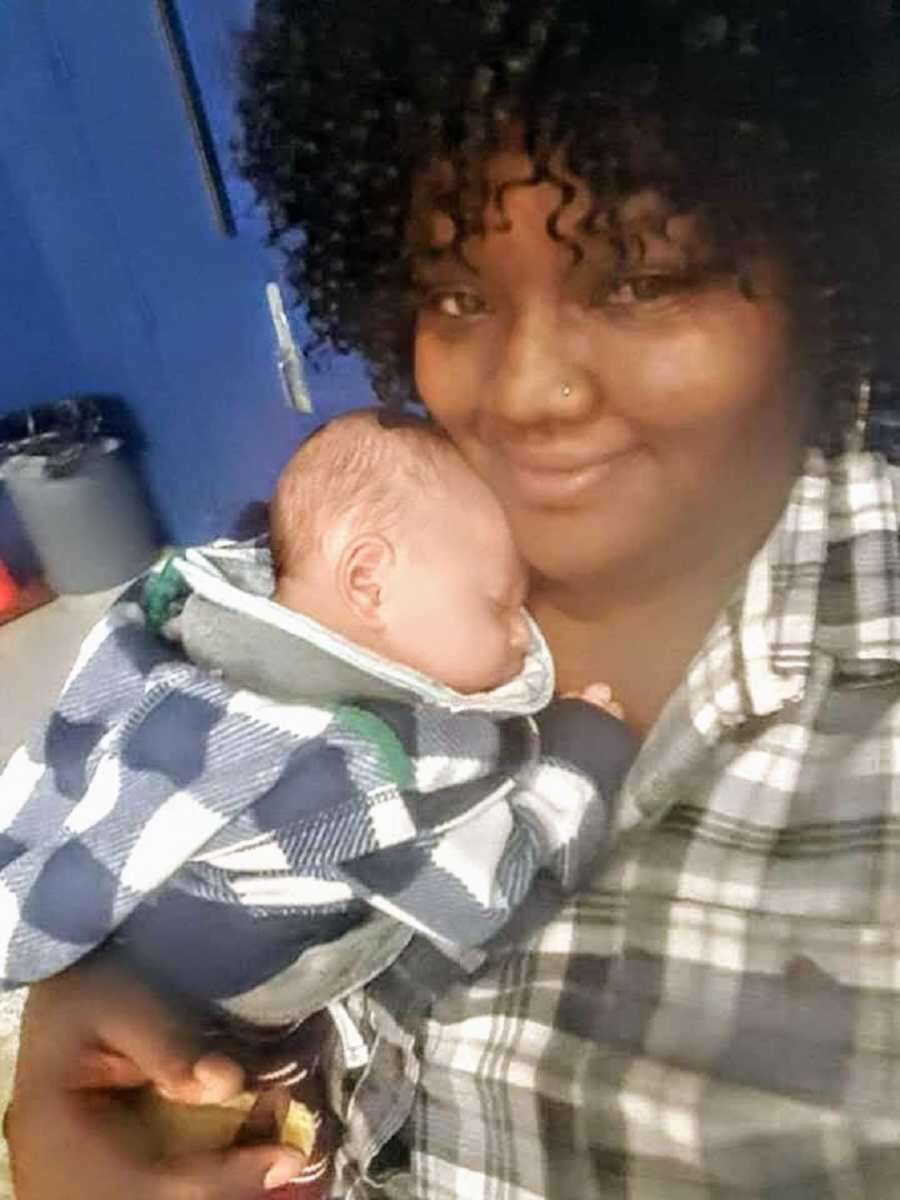 Foster mom holding newborn baby in matching plaid shirts