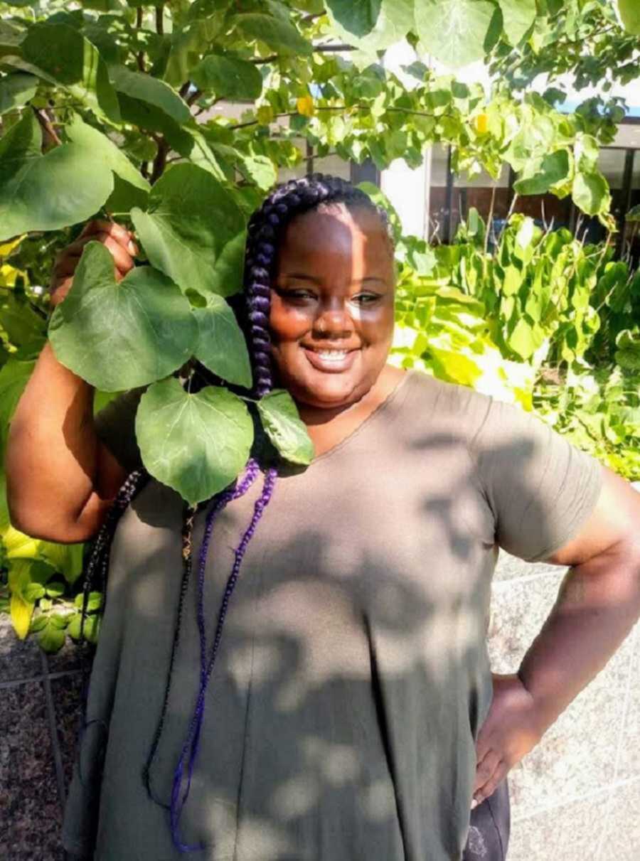 Foster mom smiling next to green leaves